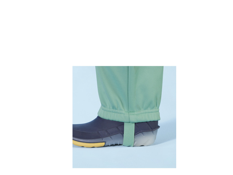 Pantalon vert avec des bottes en caoutchouc bleues.