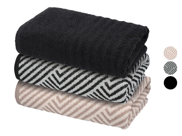 Pile de trois serviettes pliées : noire, à motifs noirs et blancs, et à motifs beiges.