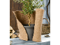 Plante en pot enveloppée dans un tapis de protection en jute, avec du bois et un panier en arrière-plan.