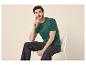 Homme en t-shirt vert et jean foncé assis sur une chaise blanche.