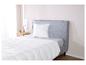 Une couette et un oreiller blancs sur un lit gris.