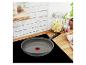 Une poêle Tefal grise sur une plaque de cuisson noire.