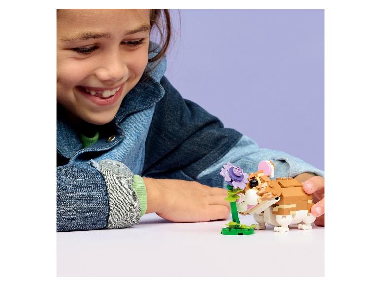 Fille jouant avec une figurine de hamster et une fleur.