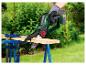 Une personne utilise une tronçonneuse Parkside sans fil pour couper un morceau de bois.