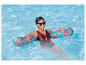 Femme relaxant dans une piscine avec des flotteurs fruités.