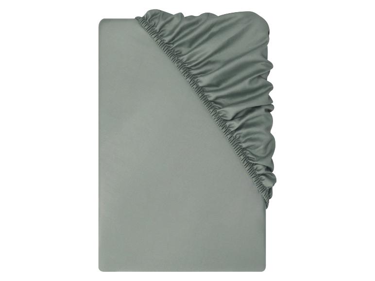 Un drap-housse vert sauge, plié pour montrer le coin élastiqué.