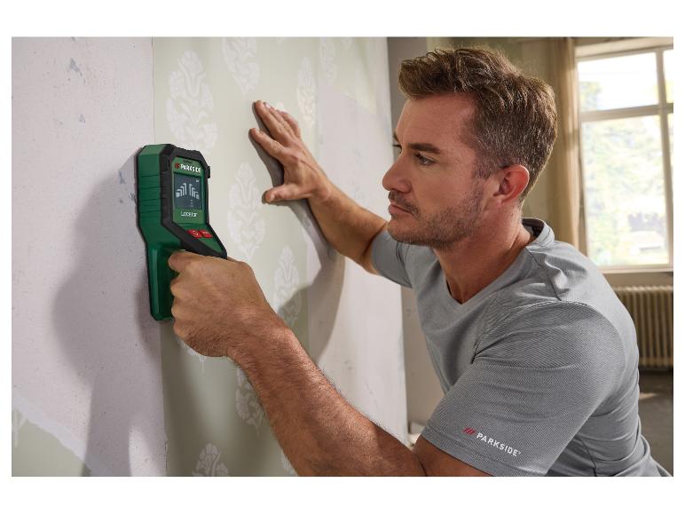 Homme utilisant un détecteur mural sur un mur tapissé.