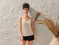 Une femme porte un débardeur beige et un short noir.