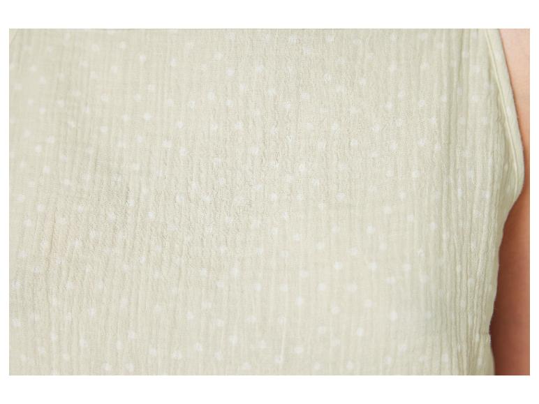 Détail d'un vêtement beige à pois blancs.