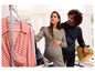 Une femme enceinte et son partenaire regardent des vêtements accrochés à un portant.