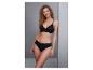 Femme en soutien-gorge et culotte noirs, appuyée contre un mur, souriante.