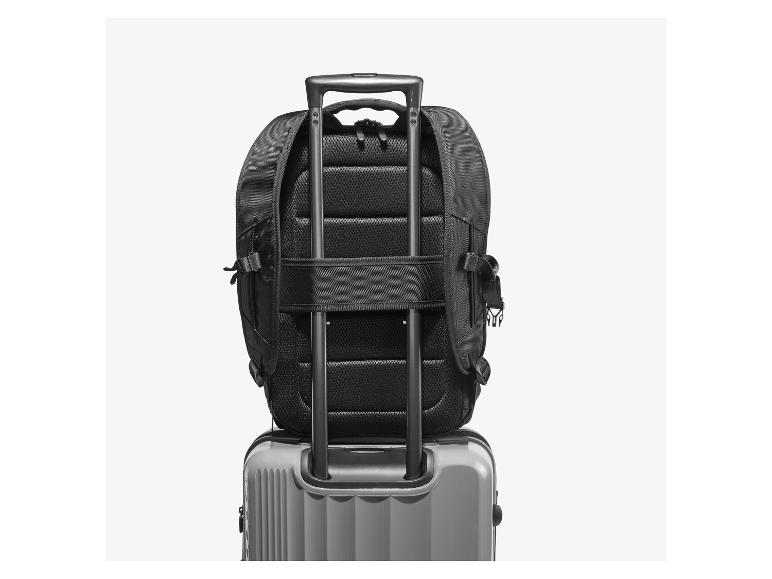 Sac à dos noir sur valise de voyage grise avec poignées déployées