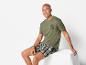 Homme portant un t-shirt vert avec l'inscription 'Raw Denim' et un pantalon de pyjama à carreaux.