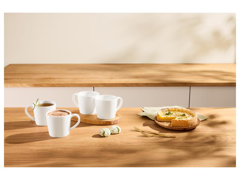 Tasses blanches avec boissons, tarte au citron et biscuits sur une table en bois.