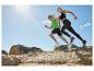 Deux athlètes courent sur des rochers sous un ciel bleu, vêtus de vêtements de sport et de chaussures de course.