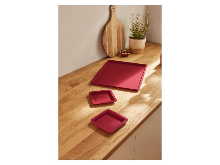 Trois plateaux carrés rouges sur une surface en bois.