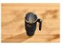 Mug thermique noir avec des accents dorés sur une table en bois.