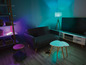 Un salon avec un canapé, une télévision et une lampe, éclairés par des lampes intelligentes colorées.