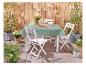 Table et chaises pliantes blanches, set de table vert, ambiance jardin.