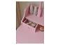 Coiffeuse rose avec tiroir ouvert, cosmétiques et flacons décoratifs.