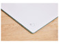 Une planche à découper en verre blanc sur une table en bois.