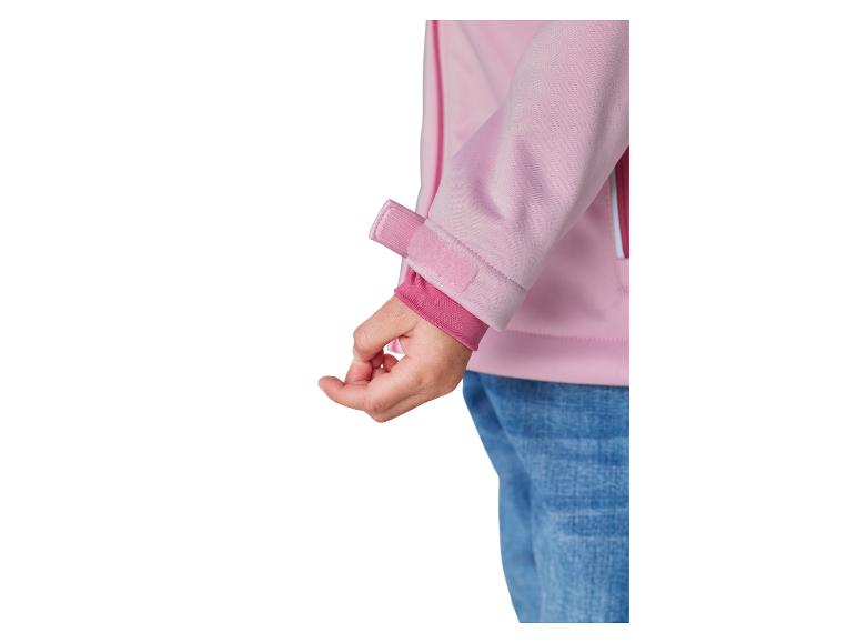 Manche de veste softshell rose avec fermeture velcro et poignet élastique, portée avec un jean.