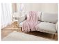 Un plaid rose clair doux drapé sur un canapé beige clair dans un salon moderne.