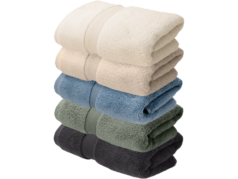 Une pile de cinq serviettes pliées de différentes couleurs sur fond noir.