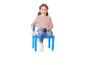 Fille joyeuse assise sur une chaise bleue, portant un pull rose et un jean.