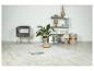 Salon moderne avec tapis clair, fauteuil gris, étagère et plantes.