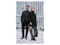 Couple en tenues noires élégantes posant devant un immeuble moderne.