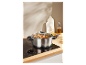 Une casserole en acier inoxydable avec un couvercle en verre sur une plaque à induction.