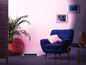 Un fauteuil bleu avec un coussin, une plante et une prise de courant dans une pièce avec des murs roses.