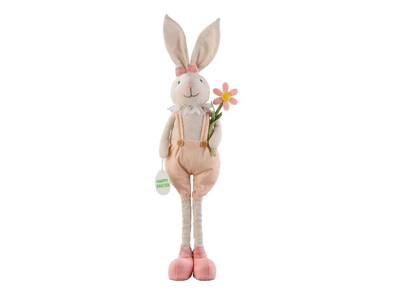 Un lapin de Pâques en peluche avec une fleur rose et une étiquette 'Happy Easter'.