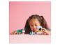 Une fille joue avec des ensembles LEGO Friends, dont un camion de crème glacée et un scooter.