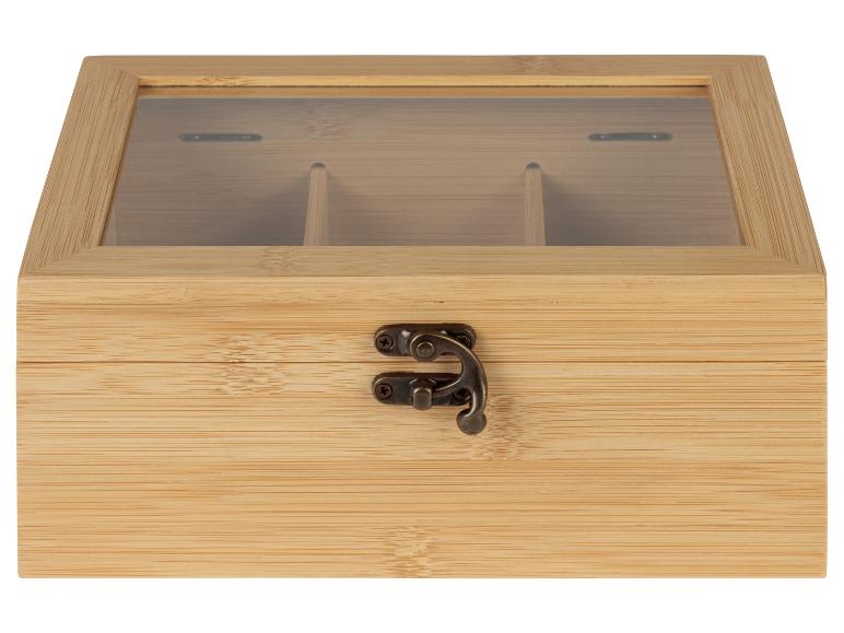 Une boîte à thé en bois avec un couvercle en verre et des compartiments pour différents types de thé.