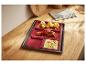 Plaque de cuisson avec inserts en silicone rouge, contenant du poulet rôti et des légumes.