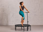 Une femme saute sur un mini trampoline avec une barre