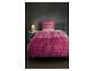 Parure de lit rose à motif géométrique sur un lit dans une chambre avec lampe de chevet.