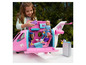 Une fillette joue avec un avion rose Barbie avec des poupées et des accessoires.
