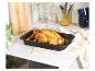 Un poulet rôti avec des légumes dans un plat allant au four noir.