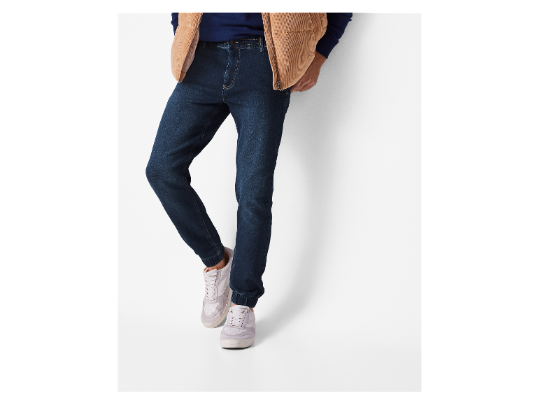 Jeans foncés avec des chevilles retroussées et des baskets blanches.