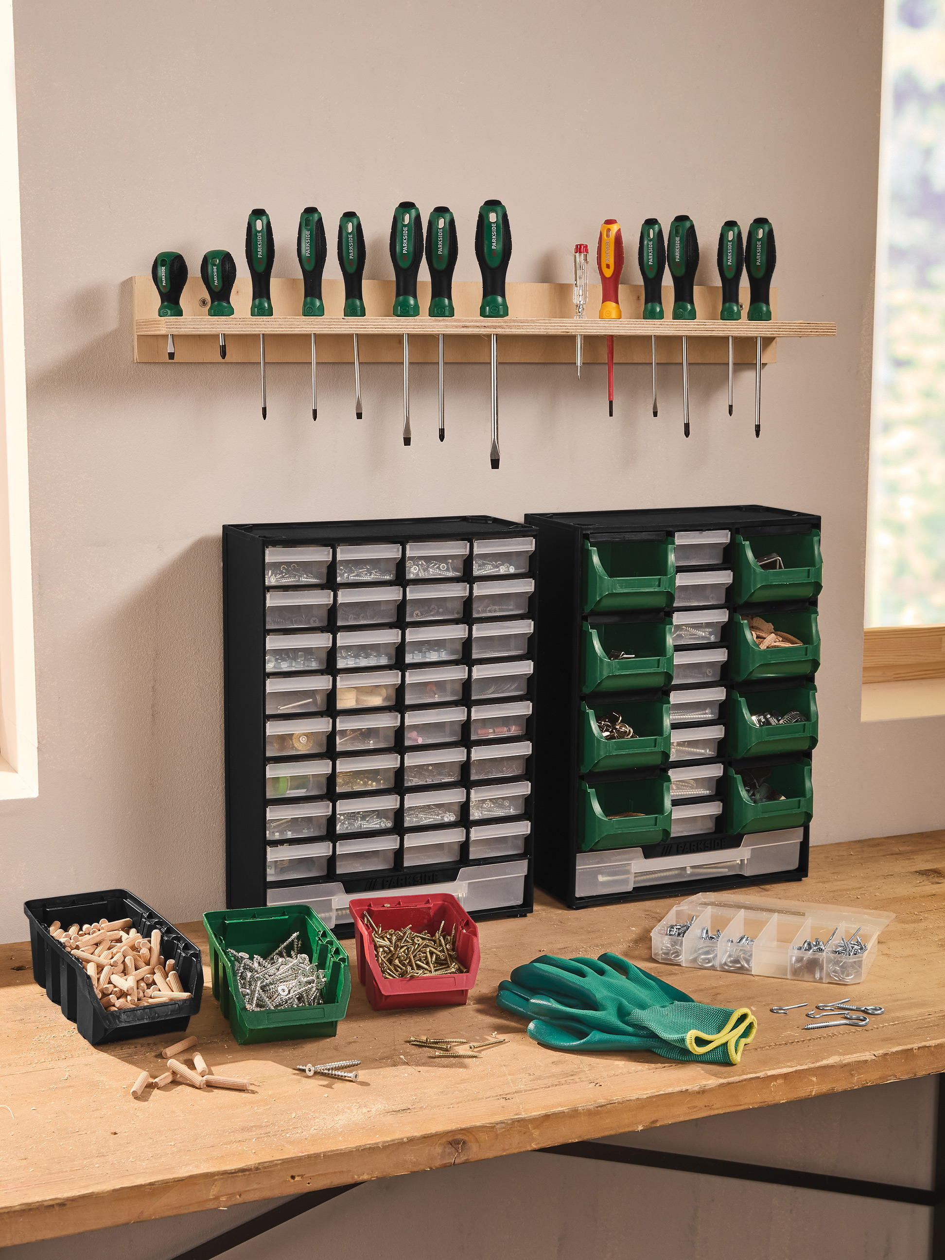 Établi de garage avec tournevis, boîtes de rangement et divers accessoires.