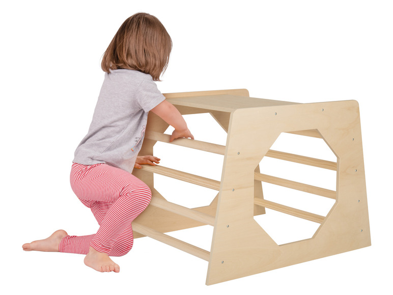 Un enfant grimpe sur une structure d'escalade en bois.