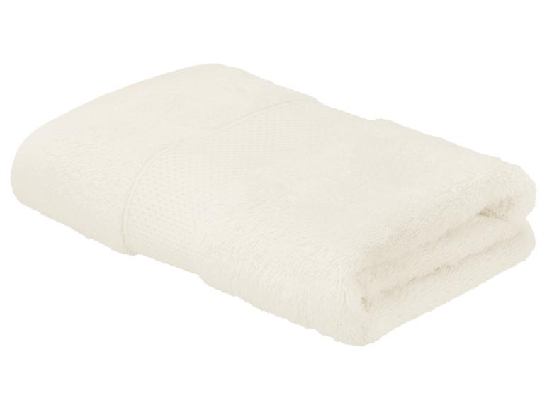 Serviette pliée de couleur crème avec une bande texturée, isolée sur fond blanc.