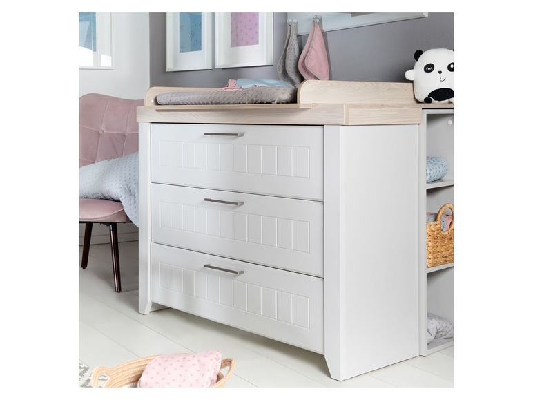 Commode blanche avec trois tiroirs et plan à langer pour bébé.