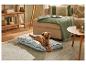 Un chien allongé sur un lit pour animal bleu clair dans un salon confortable.