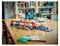 Un ensemble de train LEGO City avec gare et figurines sur une table en bois.