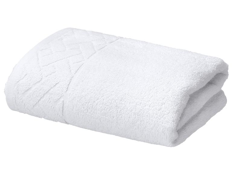 Serviette en coton blanc pliée avec un motif décoratif.