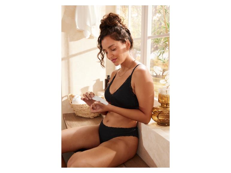 Une femme en lingerie noire utilise une lime à ongles dans sa salle de bain.
